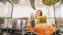A young woman is taking a clean glass out of a dish washer. A young woman is taking a clean glass out of a dish washer.