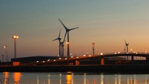 Landscape view of a bridge by the water with windmills during sunset 